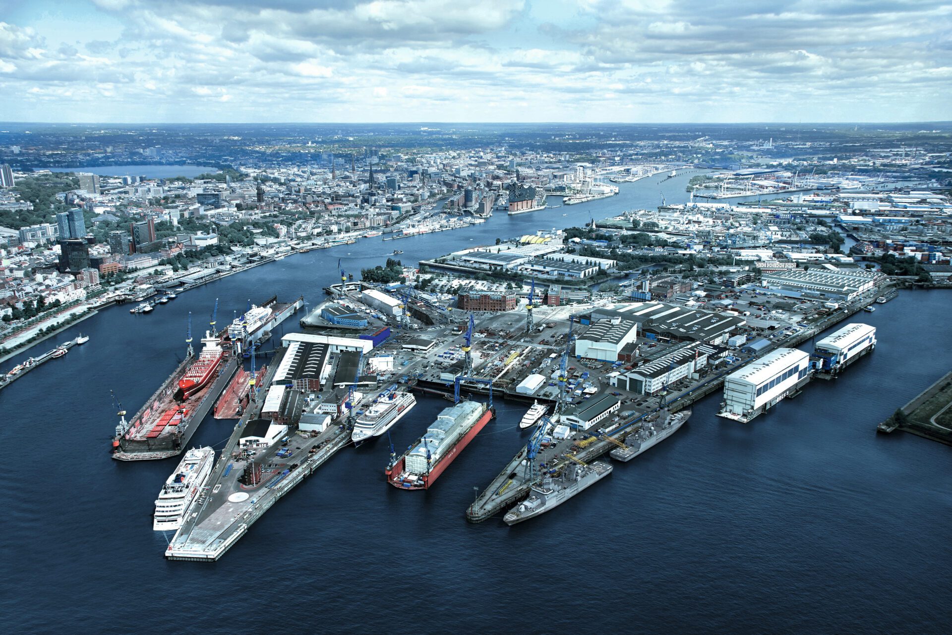 Luftaufnahme von Blohm+Voss Werft: Schiffe im Dock, Werftanlagen und Gebäude. Fokus auf Schiffbau und maritime Industrie.